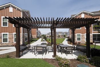 A patio with tables and chairs under a wooden pergola